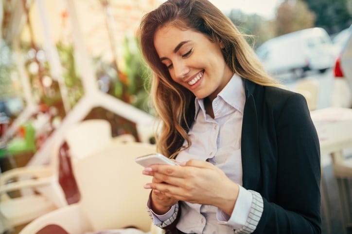 Happy businesswoman using phone outdoors