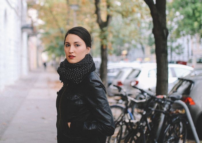 Vintage toned portrait of a young woman in Berlin, wearing a black leather jacket and a beige skirt, walking on the streets of Prenzlauer Berg, near Mitte in the late Autumn day. Street style, casual fashion concept.