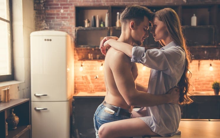 Beautiful romantic couple are hugging and smiling while spending time together in kitchen at home