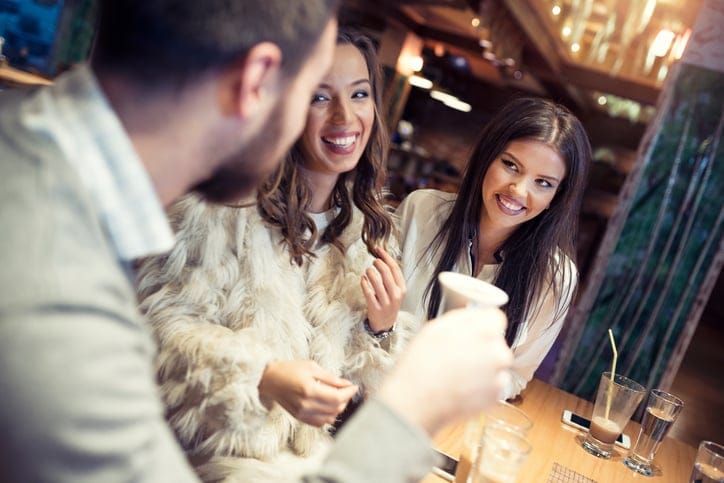 Group of friends sitting in a caffee bar, talking to each other, smiling and laughing, drinking cafe and having fun.