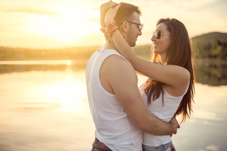 Love couple in nature enjoys on great sunset by the lake.