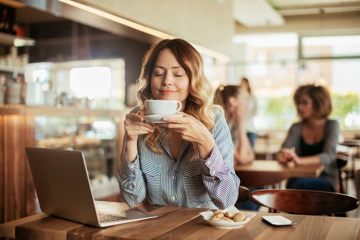 Photo of a young woman using laptop in cafe