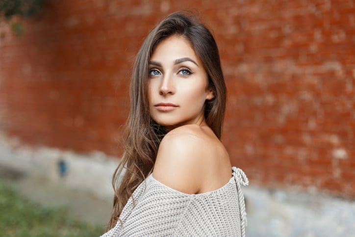 Beautiful portrait of a young pretty woman with hair in a gray vintage sweater on a red background