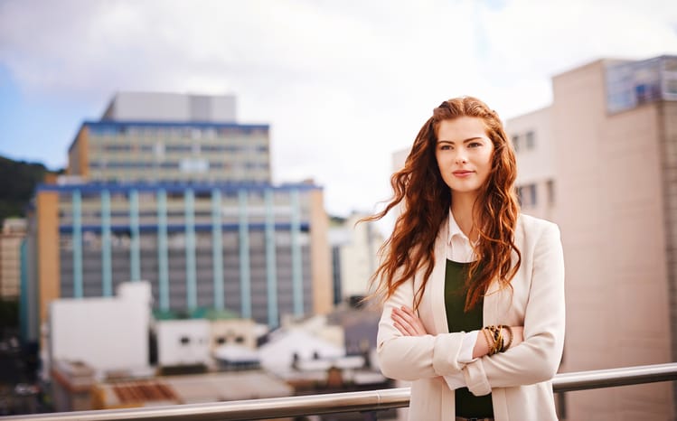 Shot of a young businesswoman standing with her arms crossed on a balcony