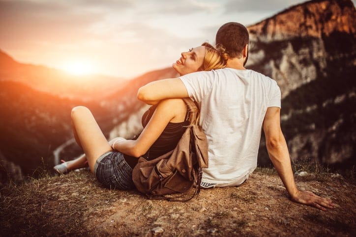 Couple in love hugging and sitting on the top of mountains and woods in summer.