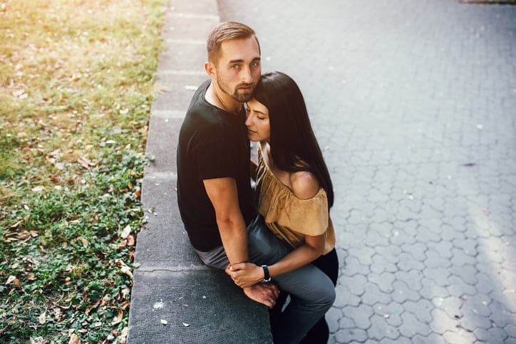 young man gently hugs girl in the park