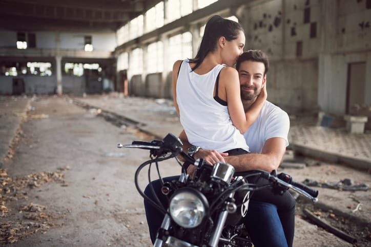 Love couple sitting on a bike in an old ruined garage.