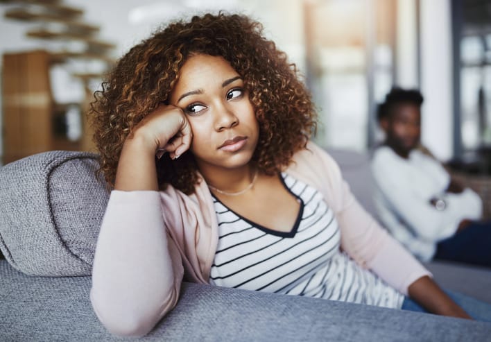 Shot of a young woman looking despondent after having a fight with her boyfriend at home