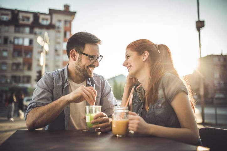 Young happy couple relaxing in a cafe during sunny day and communicating.