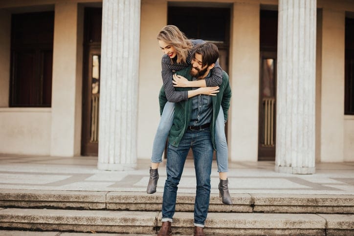 Bearded man giving his girfriend a piggyback ride