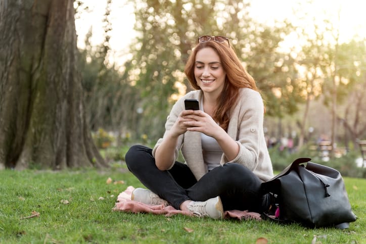 Young girl is texting using her mobile phone at the park