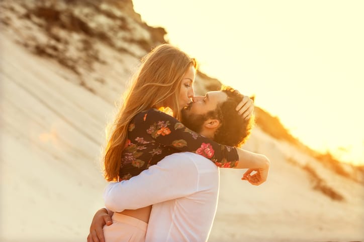 Young couple in love walking in the park holding hands looking in the sunset