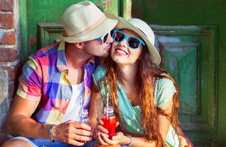 Happy young couple in the street wearing hats and sunglasses