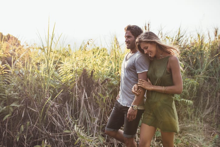 utdoor shot of romantic young couple walking together in countryside. Young man and woman on a holiday.