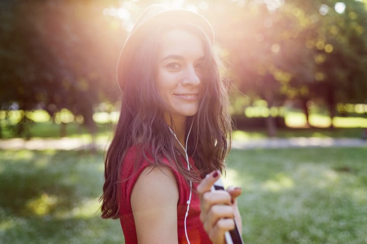 Girl listening to music, looking and smiling at camera