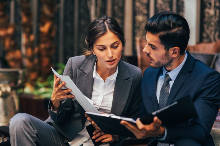 Two business people discussing a document in a meeting.