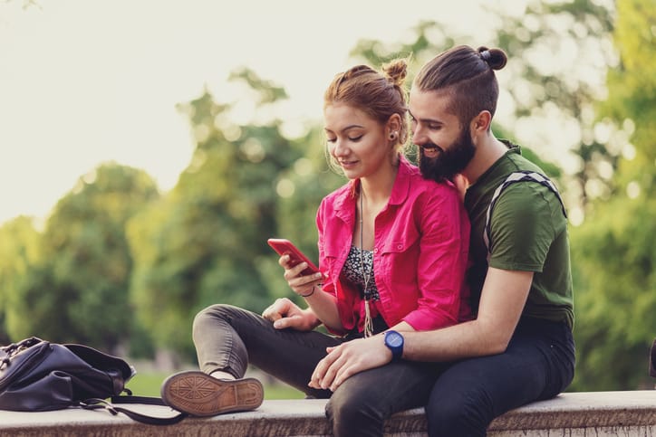 Couple spending there free time by sitting and looking at smart phone
