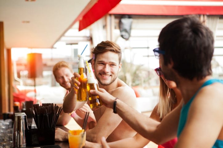 Friends having fun at beach bar drinking and talking
