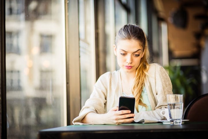 Woman drinking coffee texting, taking selfie
