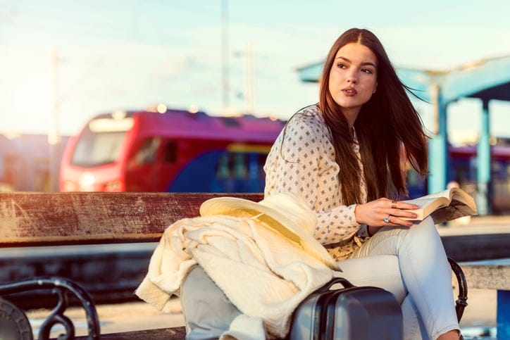 Girl on train station with luggage.
