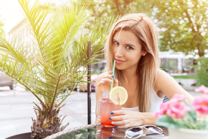 Young smiling girl drinking tasty cocktail , outdoor