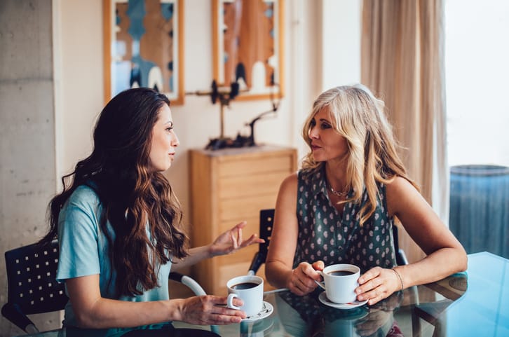 Mother and daughter drinking coffee together at home.