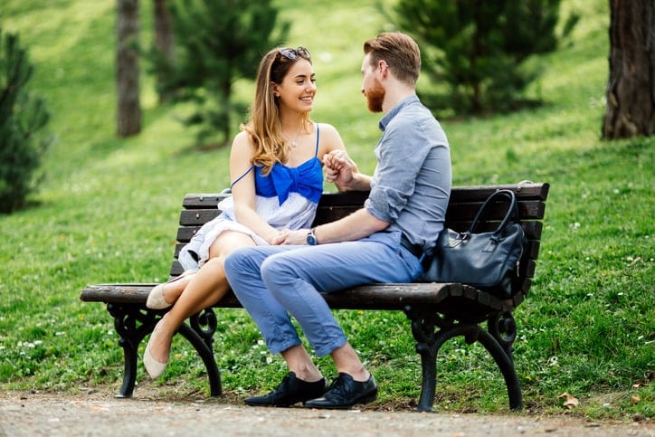 Romantic couple in park sitting on bench