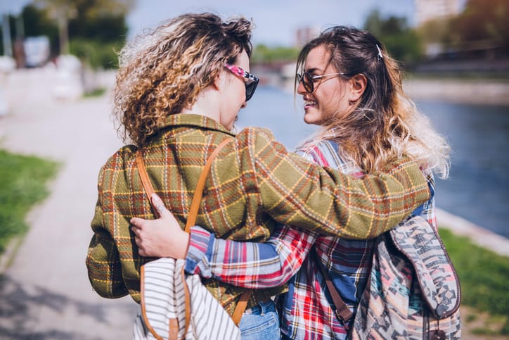Young couple of girls bonding outdoor. Walk by the river