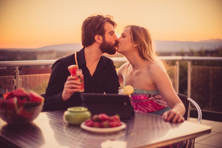 Happy young couple having fruit salad and smoothies on a summer day