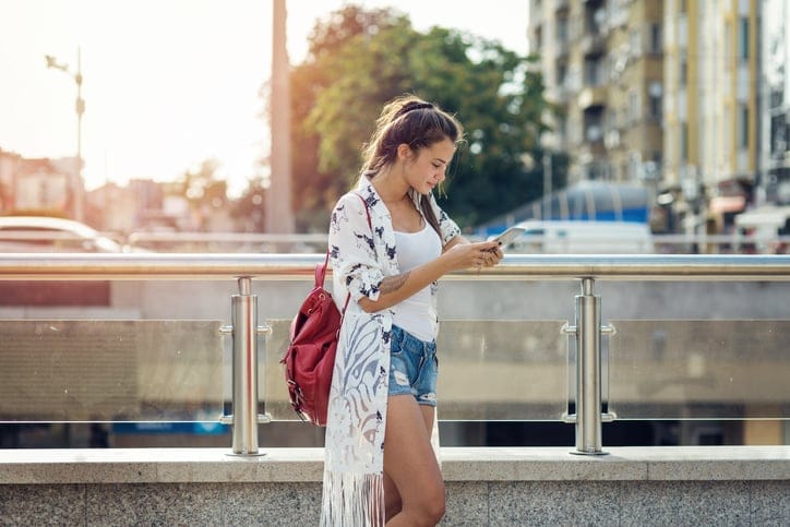 young trendy woman texting in the street