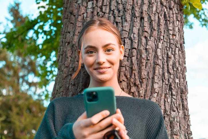Smiling woman leaning against a tree.