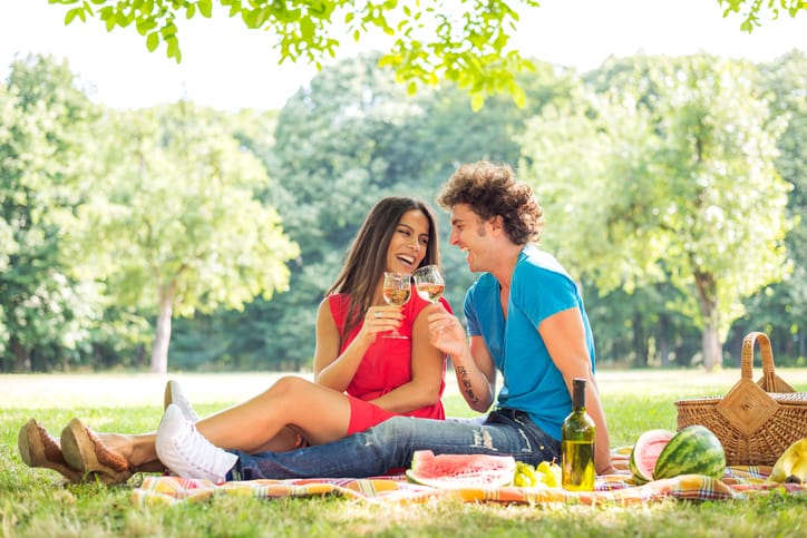 Young happy couple in love drinking white wine in the park.
