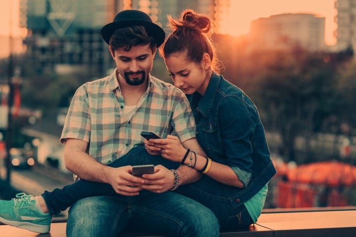 Couple using smartphones on sunset