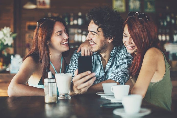 Two young women flirting with a man in cafe in the summer.