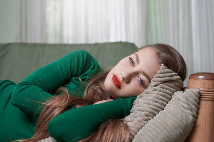 lifestyle shot of young woman lying on the sofa and feeling sleepy.