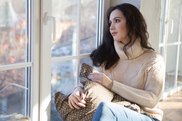 Portrait of Beautiful Young Woman Smiling in a knitted sweater about a window. Christmas morning. Fall