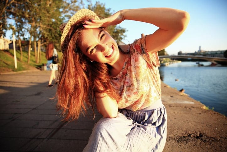 Woman with white teeth smiling in a park in the summer.
