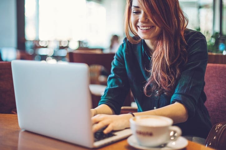 Smiling young woman working on a laptop in coffee shop