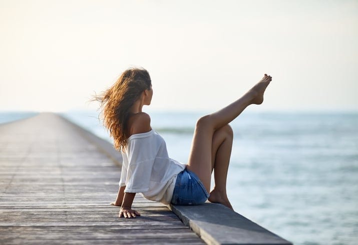Sexy beautiful woman relaxing on pier with sea view. Vacation concept