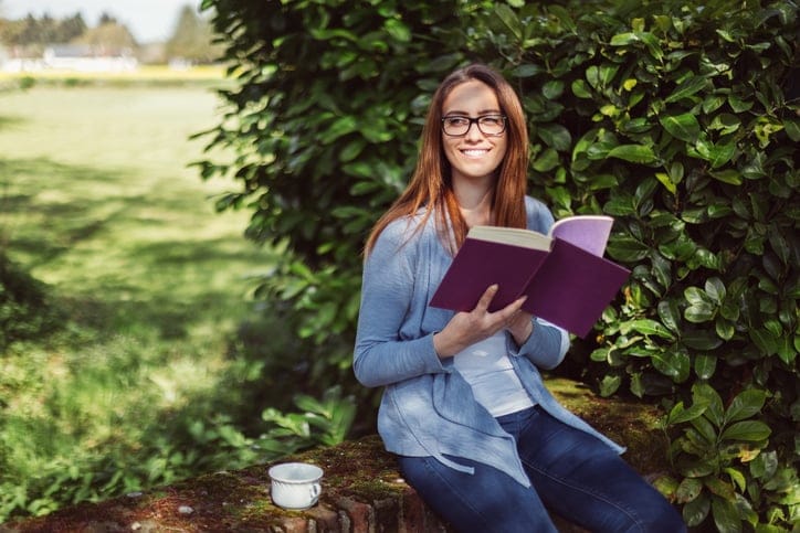 Woman drinking tea and reading a book at the veranda