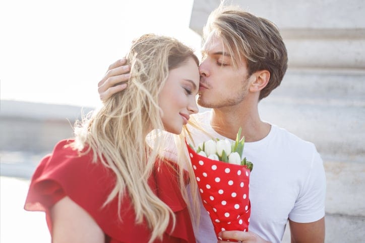 Young blonde man hug woman forehead outdoor