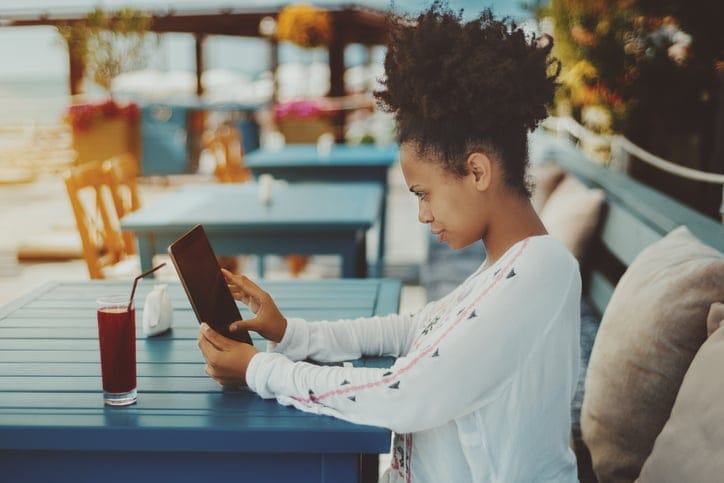 Black girl with digital pad in street cafe