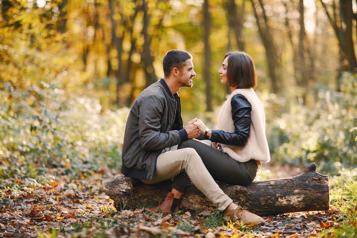 lovely couple sitting in the park during autumn
