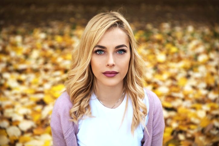 Portrait of beautiful blonde girl sitting in park