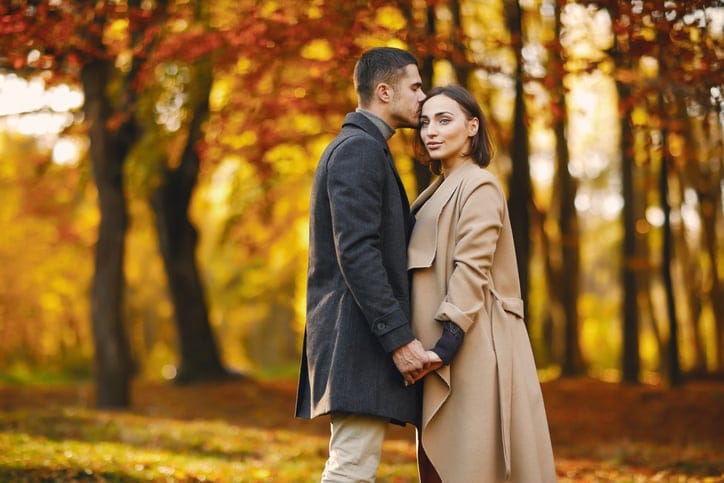 lovely couple walking around the park during autumn