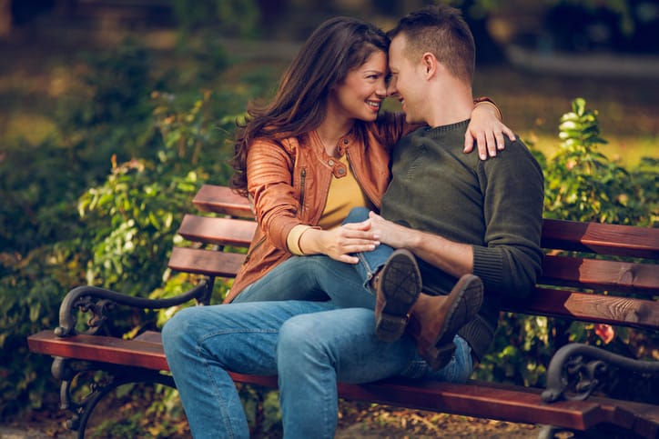 Embraced couple sitting on the bench in autumn park