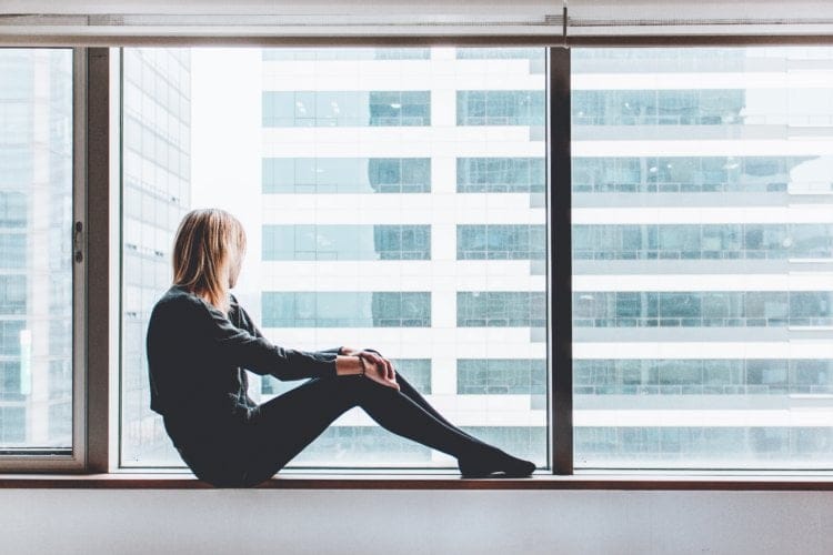 woman sitting alone on windowsill