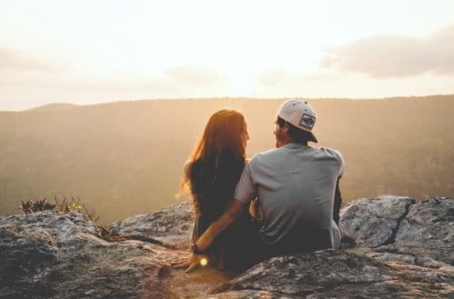 couple sitting hillside sunset