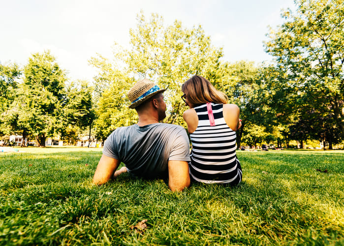 Young heterosexual couple in casual clothes relaxing in park