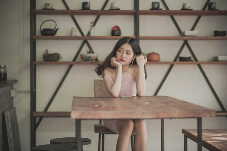 Woman sitting in front of a minimalist bookshelf.